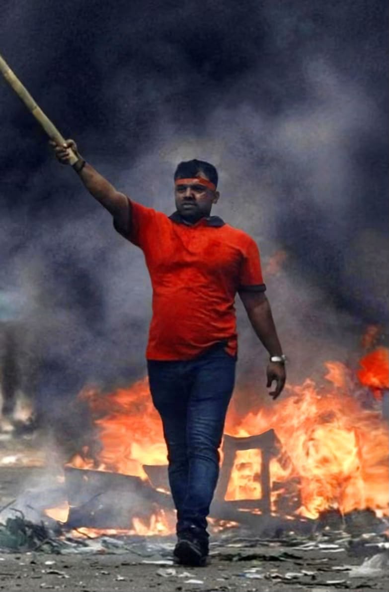 Sajjadul Miraj on the street with a raised stick amid burning barricades during an anti-fascist protest